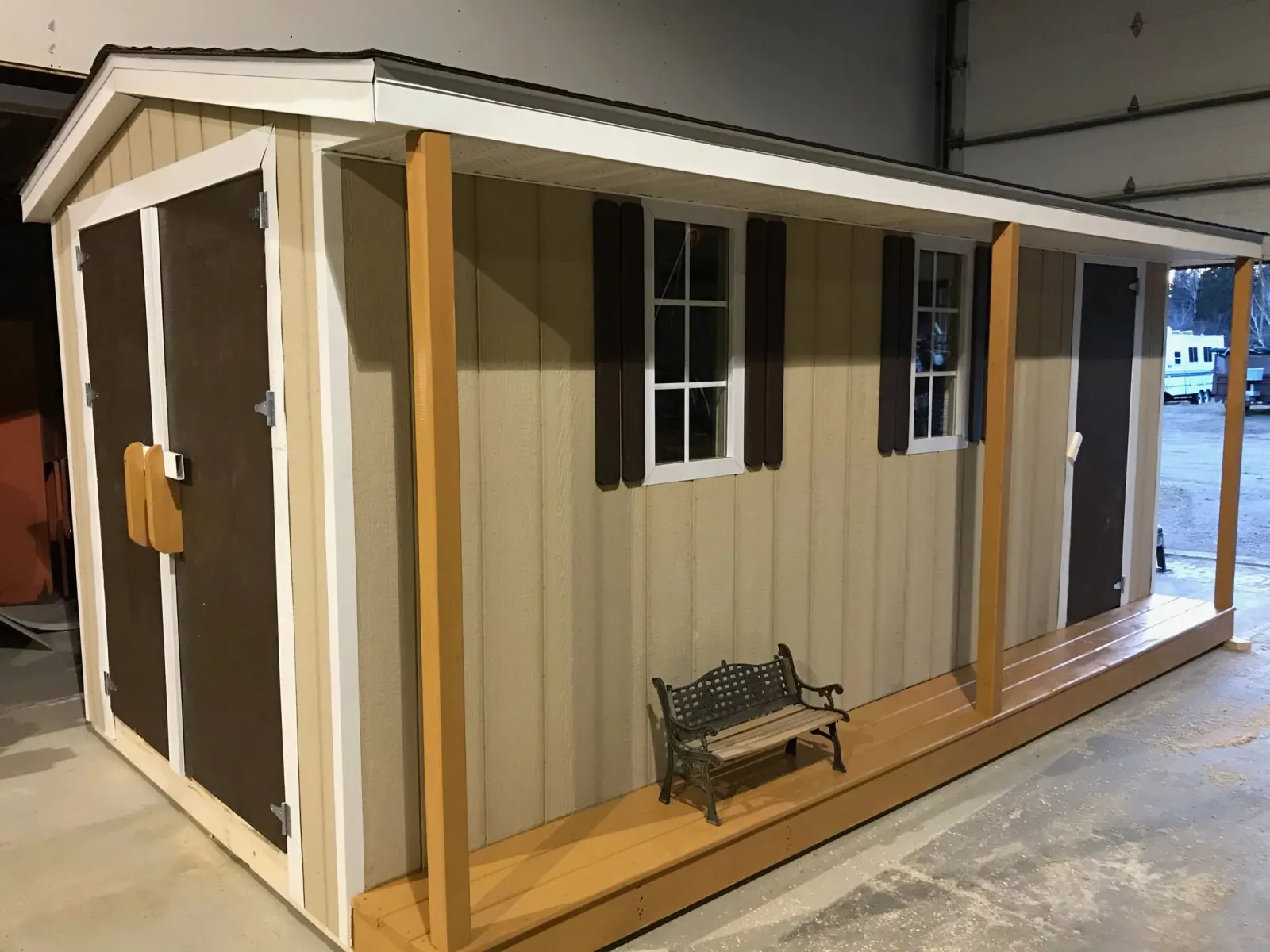 Shed with a covered porch, timber posts, shuttered windows and two brown doors, finished inside the workshop